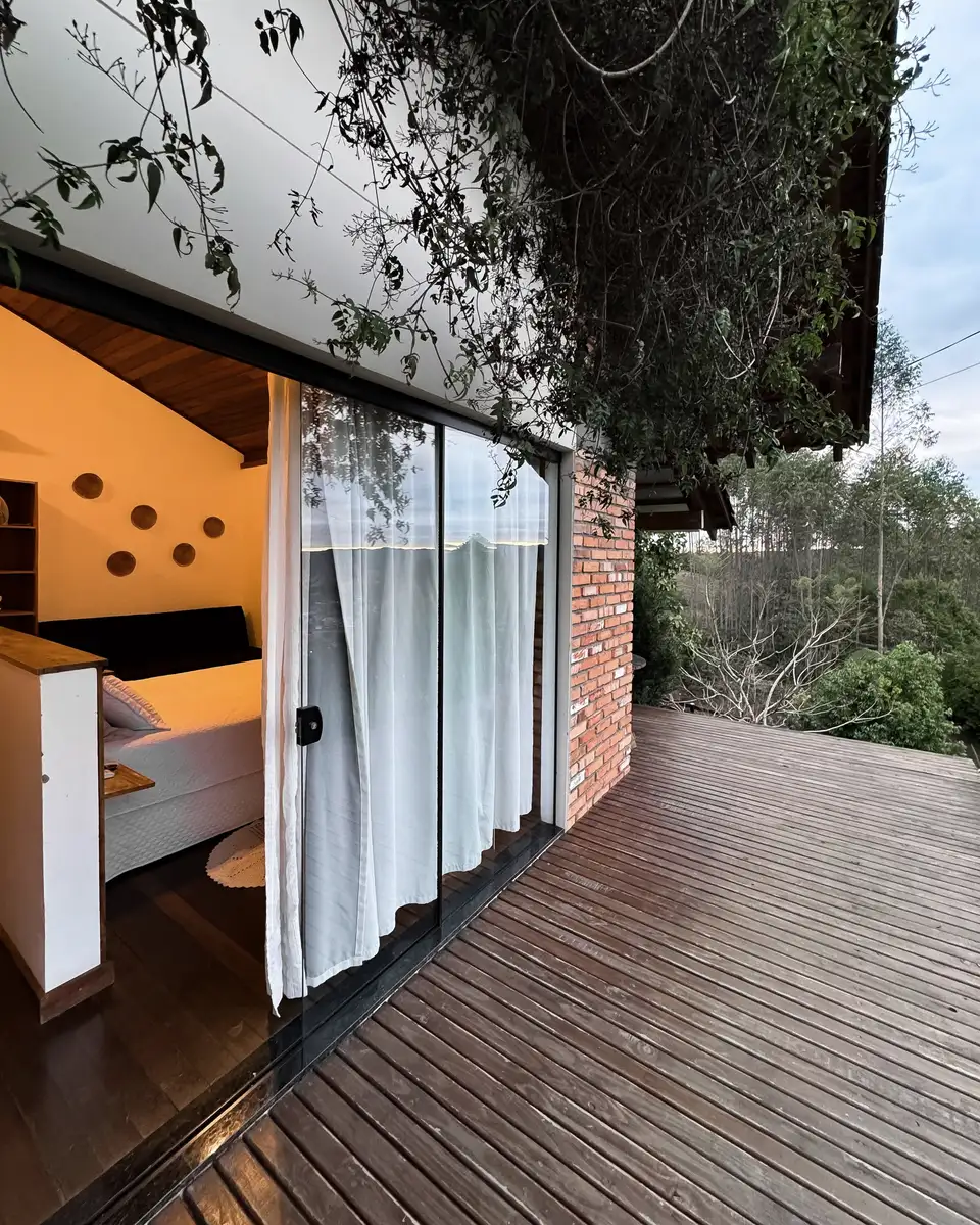 An open sliding door from a brick house onto a timber deck with plants