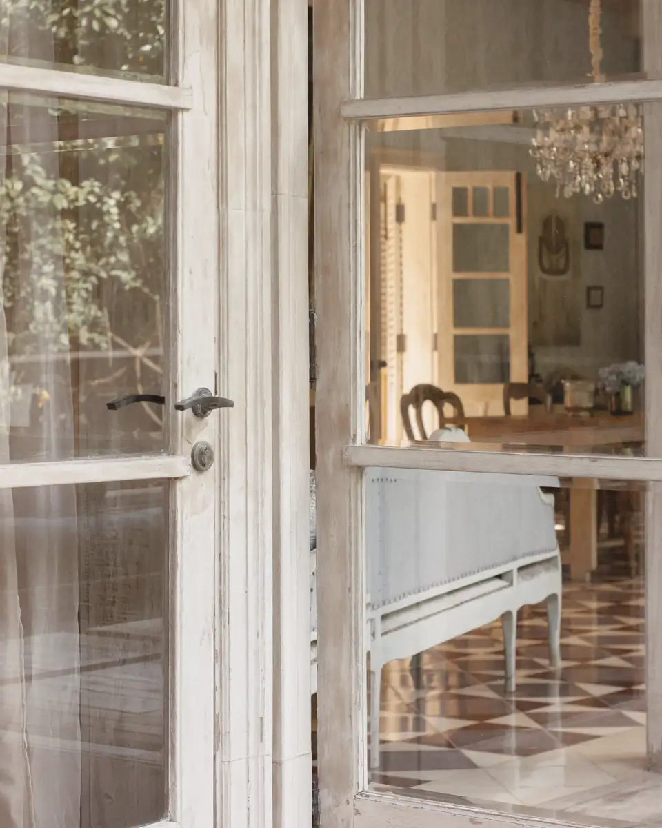 Open French doors looking into a bright room with a chandelier