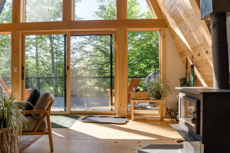 Tall glass doors and windows opening a wood-lined room onto a deck