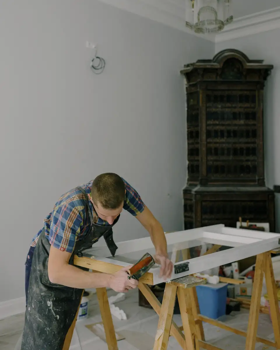 A carpenter repairing an old wooden window sash in a bright room